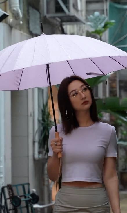 高海寧 高海寧身穿緊身白色上衣配杏色長裙，手持粉色雨傘在雨中漫步，場面非常浪漫。