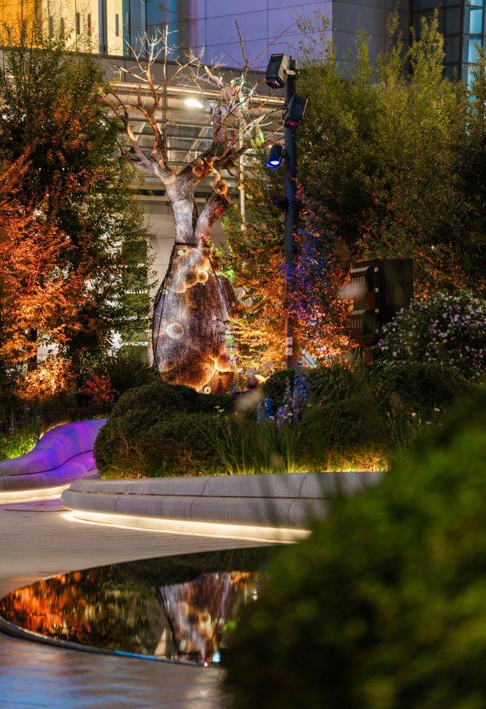 德國數碼藝術家 Philipp Frank 創作的全球首個永久擺放的數碼光影藝術裝置《Hypnotic Dream》，捕捉樹木的頻率變化，將其轉化為抽象光影及音效，利用數碼技術投射於花園中擁有 200 年歷史的佛肚樹上。（圖片來源：恒地提供）