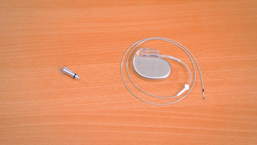 心跳過慢 傳統起搏器(右)由主機連接電線,經靜脈伸入心臟內發出微小電波刺激心跳;無導線起搏器(左)體積只有維他命丸般大,整粒可直接放入心室或心房內。(圖片來源:日日健康)